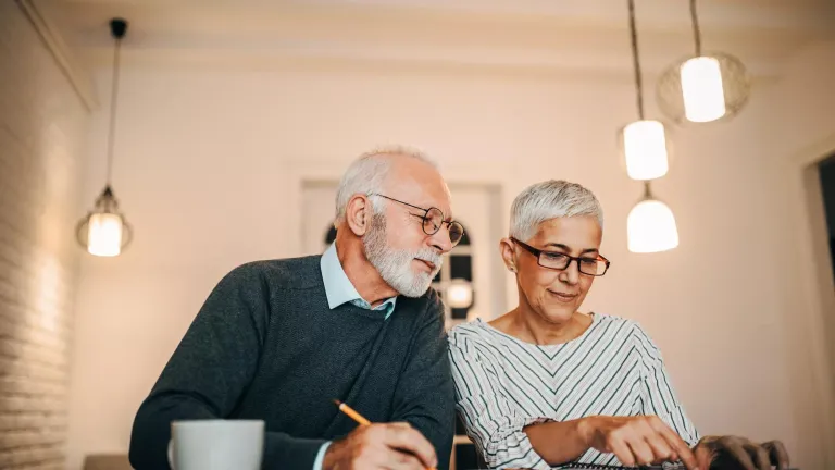 Man and woman reviewing finances with calculator and notebook.