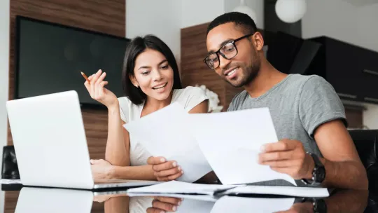 Young man and woman working together at a table to create a retirement plan.